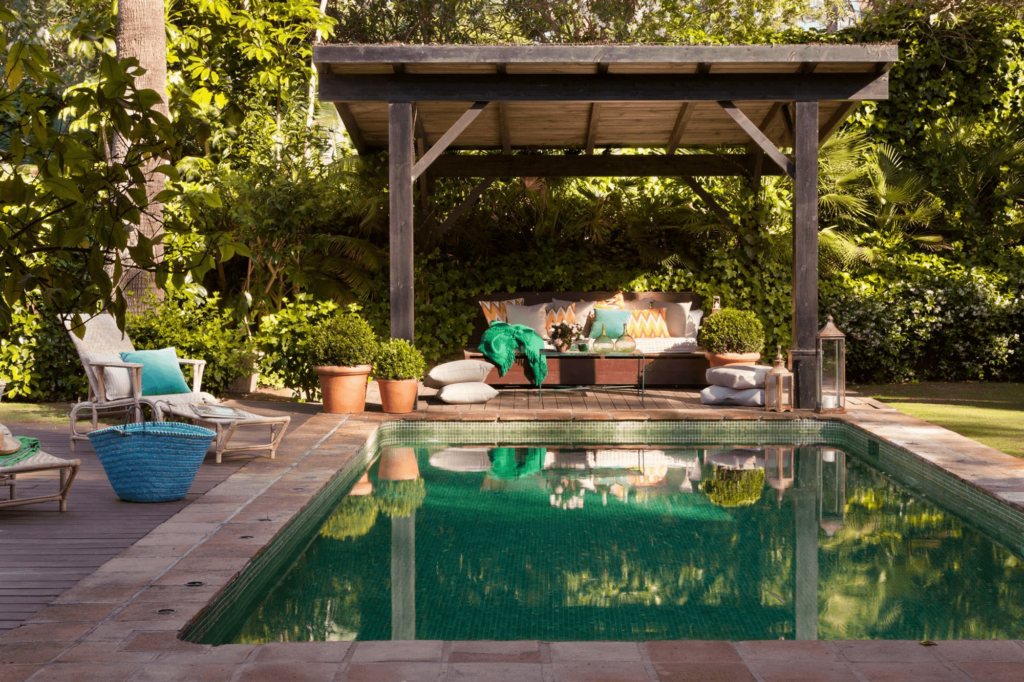 Al lado de una piscina, una pérgola de madera.