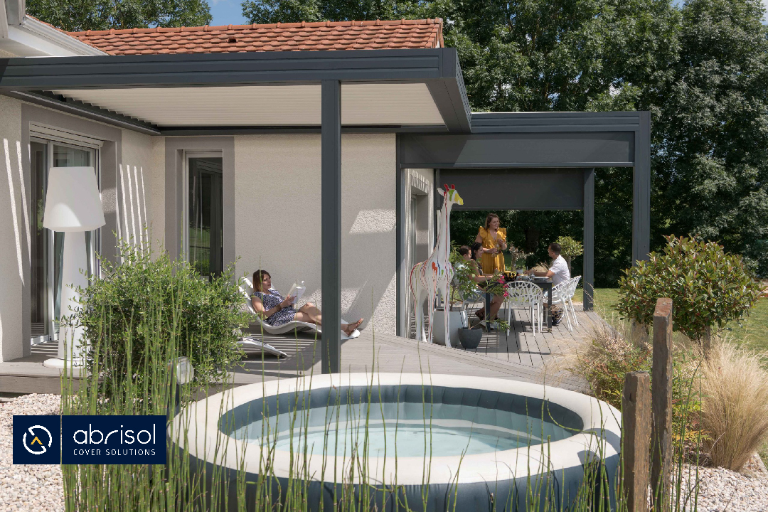 Pérgola exterior adosada en la que una familia disfruta de la sombra.