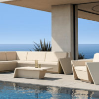 Al lado de una piscina, mobiliario de exterior en color beige: un sofá, un sillón y una mesa de centro.